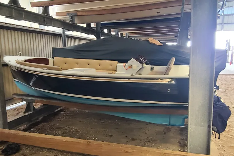 The Image of 2019 Duffy 18 boat in storage, featuring a sleek blue hull and beige interior. - 0