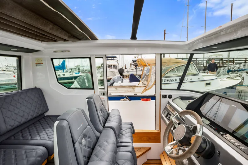 Slide: The Image of Interior of 2021 Axopar 28 Cabin boat with modern seating and steering wheel. - 24
