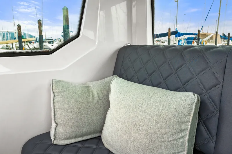 Slide: The Image of Interior of 2021 Axopar 28 Cabin with quilted seating and cushions, marina view. - 31