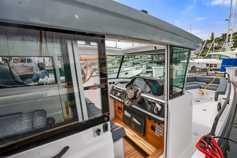 Slide: The Image of 2021 Axopar 28 Cabin boat interior with steering wheel and seating area. - 14