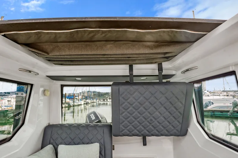 Slide: The Image of Interior view of 2021 Axopar 28 Cabin boat with quilted seating and marina backdrop. - 28