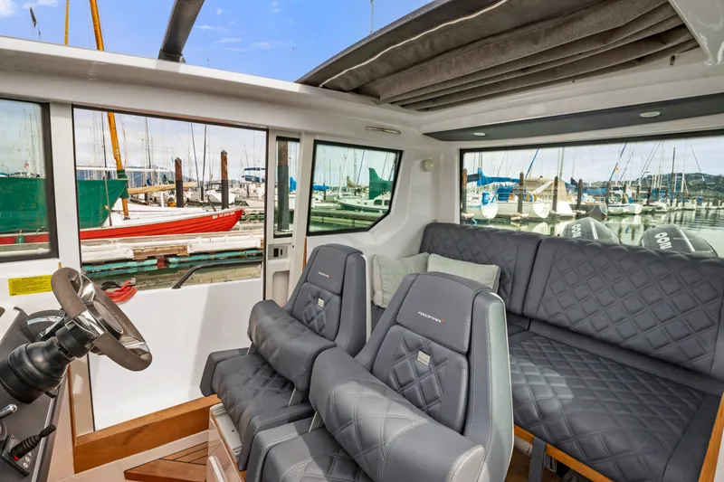 Slide: The Image of Interior of 2021 Axopar 28 Cabin boat with quilted seating and marina view. - 26