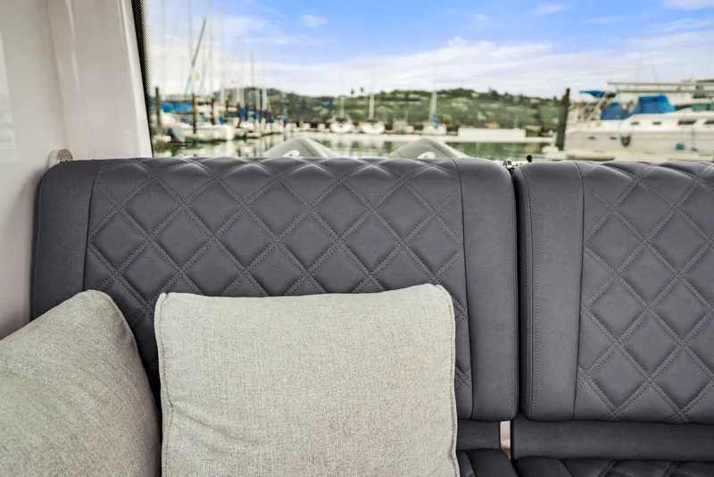 Slide: The Image of Gray quilted seating with cushions inside a 2021 Axopar 28 Cabin boat, marina view. - 17