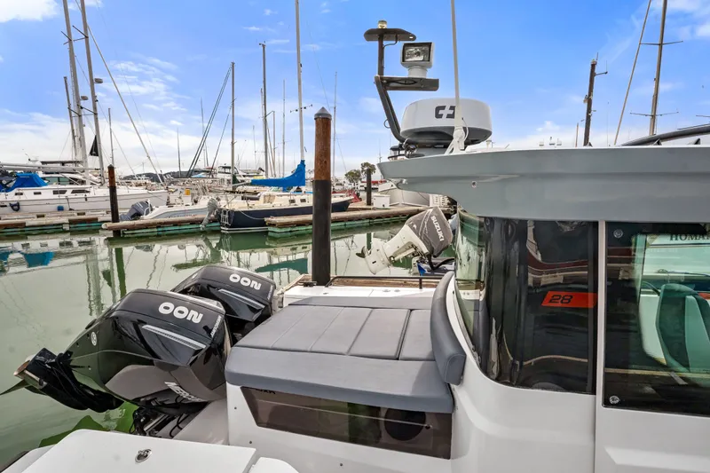 Slide: The Image of 2021 Axopar 28 Cabin boat docked in a marina with twin outboard engines. - 2