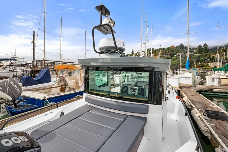 Slide: The Image of 2021 Axopar 28 Cabin boat docked at a marina, surrounded by other vessels. - 12