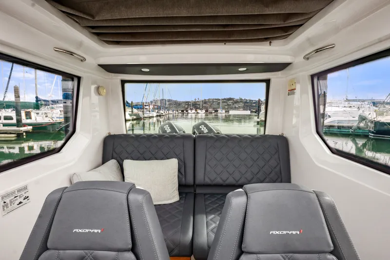 Slide: The Image of Interior of 2021 Axopar 28 Cabin boat with plush seating and marina view. - 25