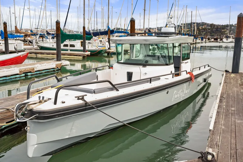 Slide: The Image of 2021 Axopar 28 Cabin boat docked in a marina with sailboats in the background. - 4