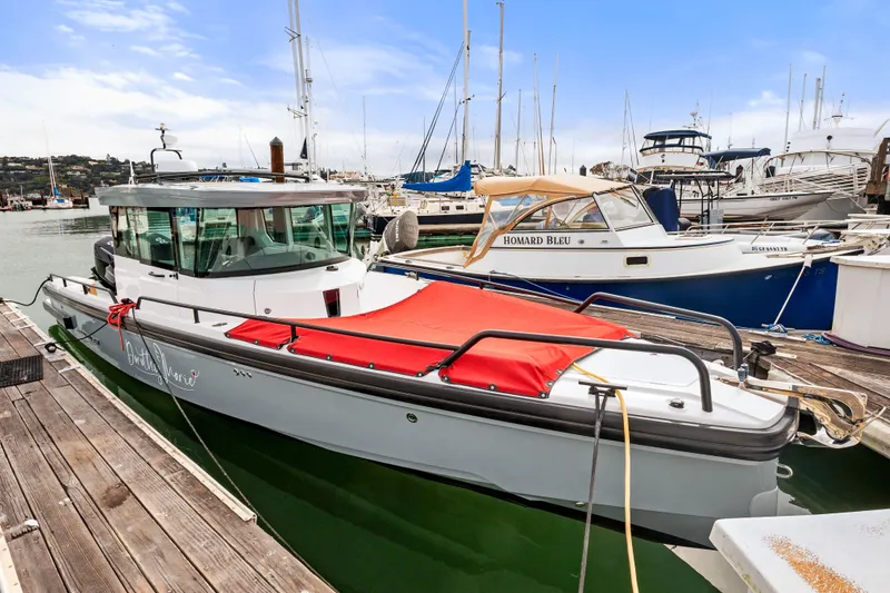 Slide: The Image of 2021 Axopar 28 Cabin boat docked at a marina with other vessels. - 40