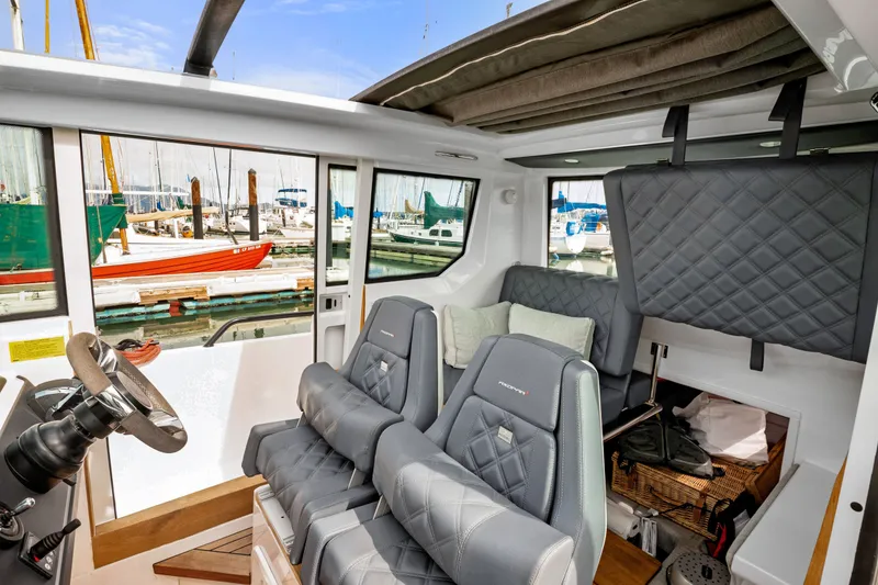 Slide: The Image of Interior of 2021 Axopar 28 Cabin boat with luxurious seating and marina view. - 29