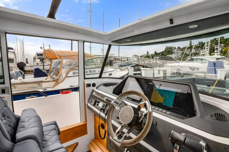 Slide: The Image of Interior view of 2021 Axopar 28 Cabin boat with modern dashboard and marina background. - 23
