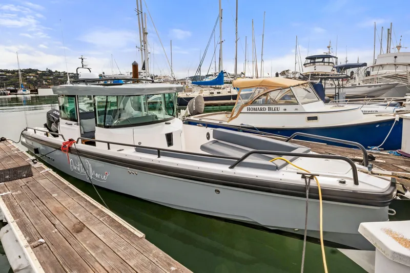 Slide: The Image of 2021 Axopar 28 Cabin boat docked at a marina with other vessels. - 3