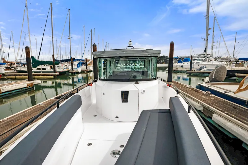 Slide: The Image of 2021 Axopar 28 Cabin boat docked in a marina with sailboats in the background. - 8