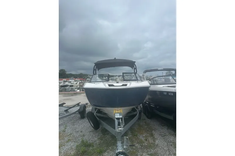 Slide: The Image of 2025 Yamaha Boats AR220 on trailer under cloudy sky at marina. - 2