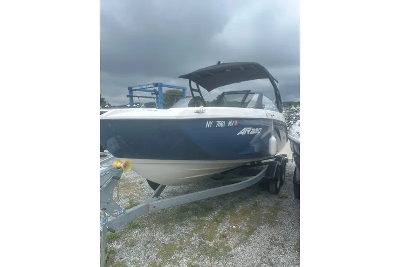 Slide: The Image of 2025 Yamaha Boats AR220 on trailer, parked outdoors under cloudy sky. - 1