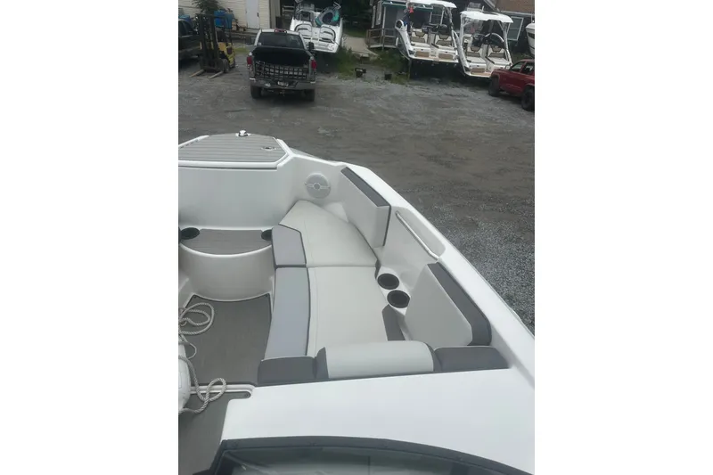 Slide: The Image of 2025 Yamaha Boats AR220 interior with spacious seating and cup holders, parked in a lot. - 7