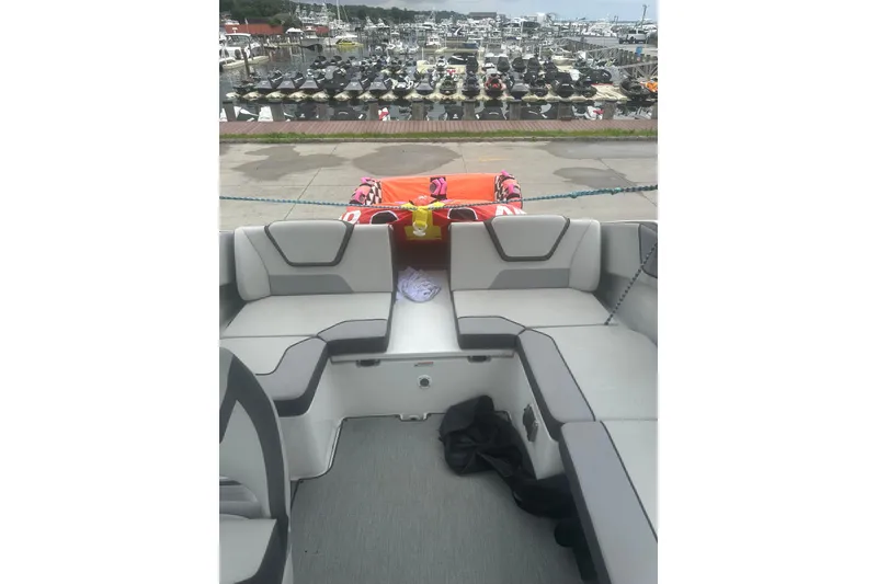 Slide: The Image of 2025 Yamaha Boats AR220 interior with gray seating, docked at a marina. - 16
