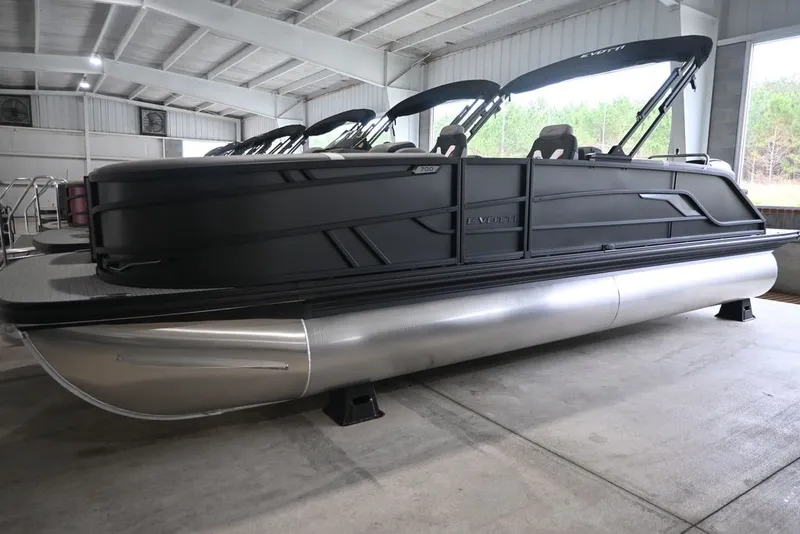 The Image of A modern pontoon boat with a black hull and silver pontoons is in a warehouse. - 1