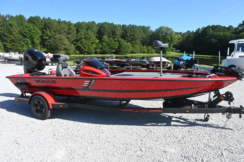 The Image of A red 2027 Vexus AVX1880 boat on a trailer in a gravel lot. - 1