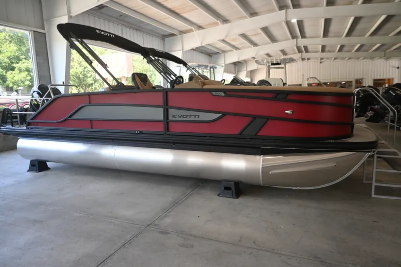The Image of A red Evotti 521CS pontoon boat from 2027 is in a warehouse on a trailer. - 1