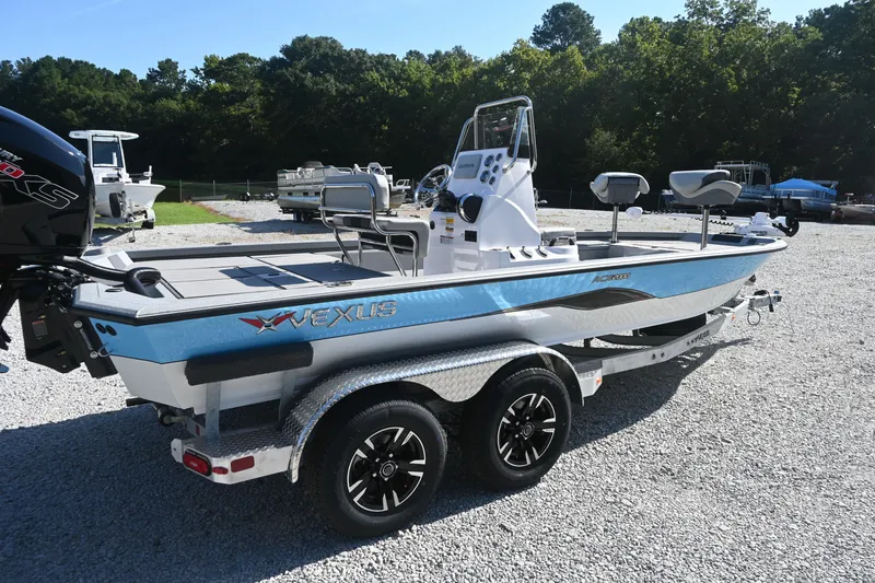 Slide: The Image of A modern Vexus ACX2000 boat on a trailer, surrounded by trees and other boats. - 2