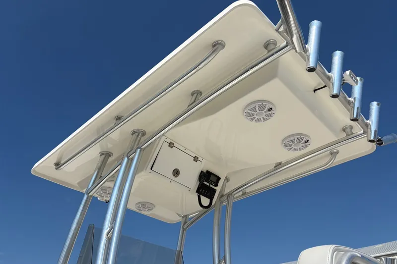 Slide: The Image of 2021 KenCraft BAYRIDER 2260FS boat T-top with rod holders and speakers against blue sky. - 11
