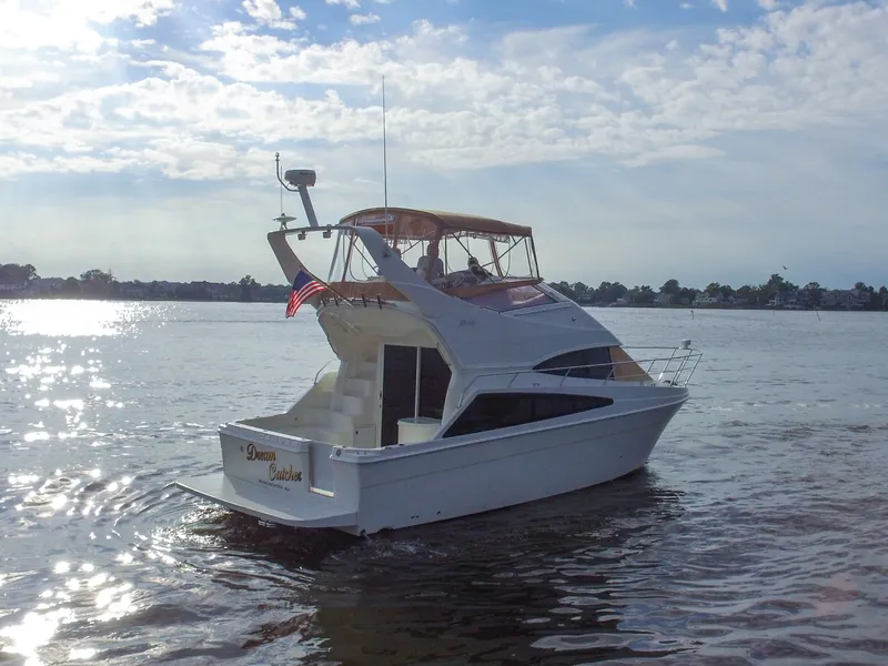 Slide: The Image of Eine Carver 33 Super Sport von 2006 fährt auf ruhigem Wasser. Sie hat ein erhöhtes Steuerhaus und eine amerikanische Flagge. - 4