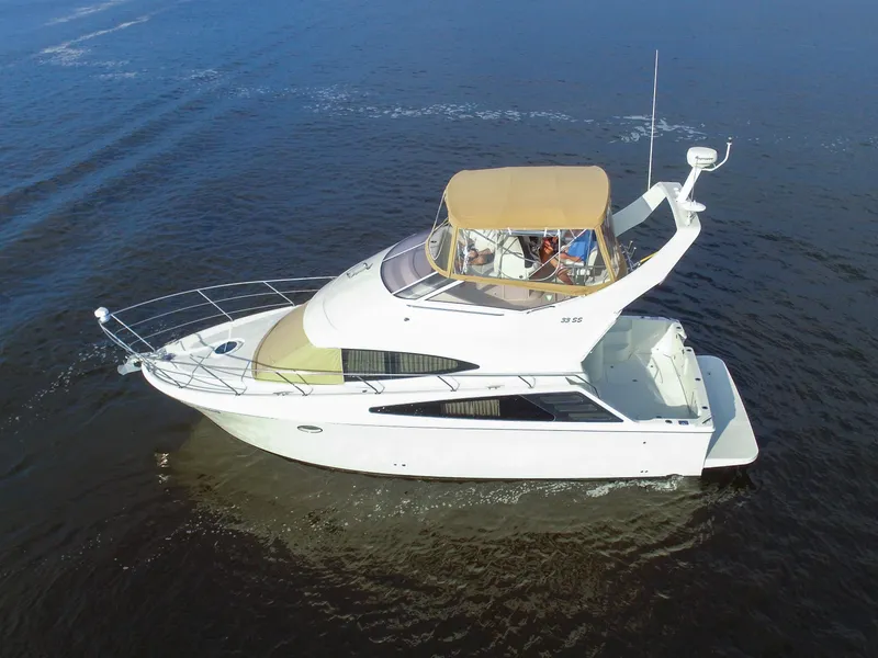 Slide: The Image of The 2006 Carver 33 Super Sport cruises on calm waters. It features a spacious deck and covered helm. - 7