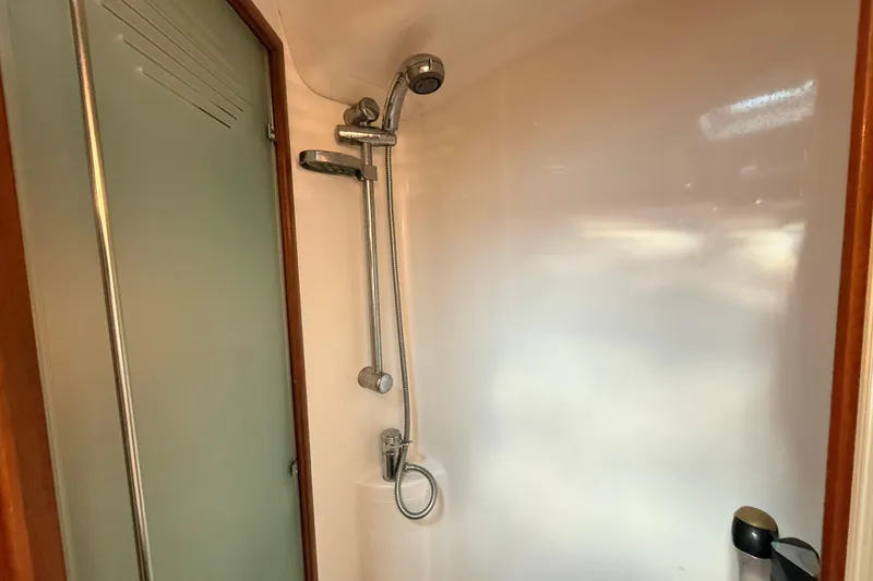 Slide: The Image of Shower area in a 2005 Beneteau 57 yacht, featuring chrome fixtures and frosted glass door. - 21
