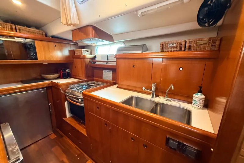 Slide: The Image of Luxurious 2005 Beneteau 57 yacht kitchen with wooden cabinetry and modern appliances. - 13