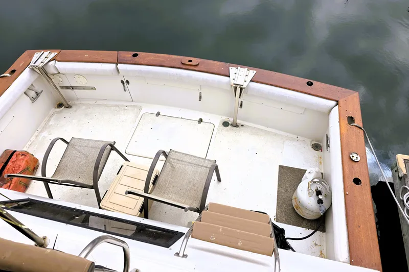 Slide: The Image of 1984 Californian 43 Motoryacht deck with chairs and propane tank by the water. - 29