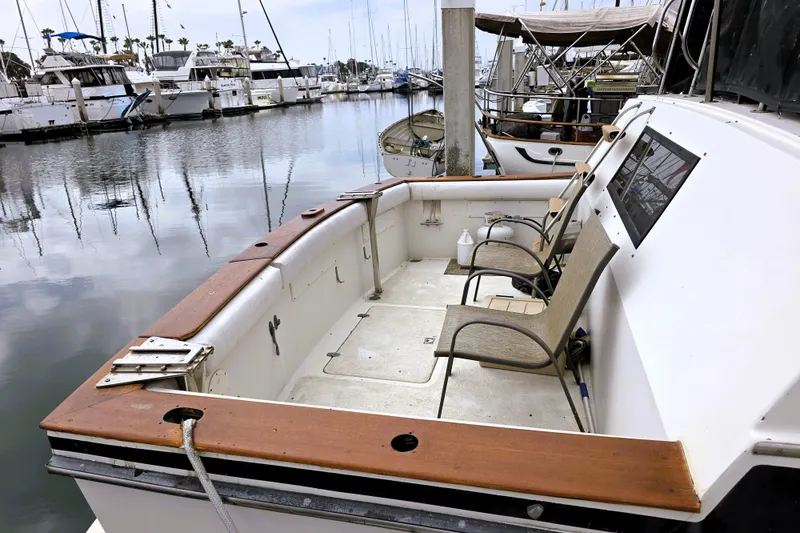 Slide: The Image of 1984 Californian 43 Motoryacht docked, featuring spacious deck with chairs and marina view. - 27