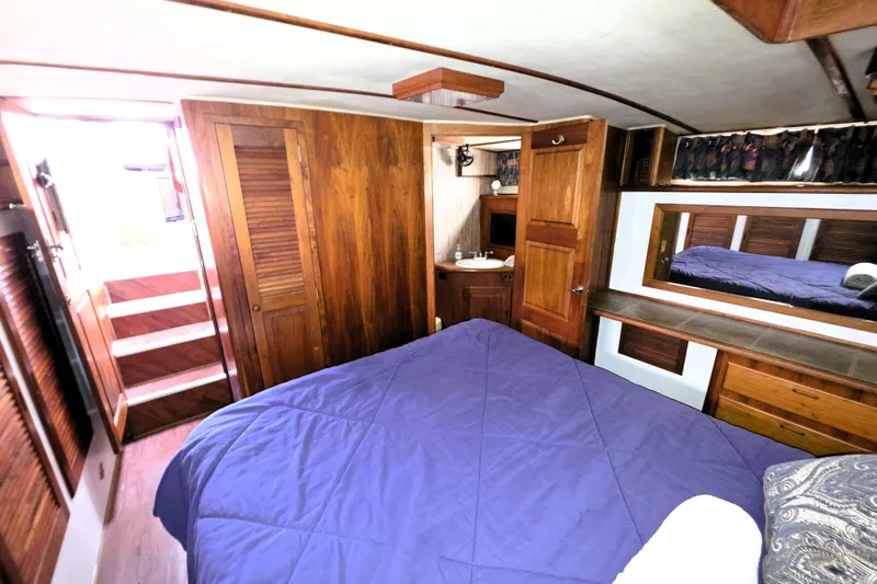 Slide: The Image of 1984 Californian 43 Motoryacht bedroom with wood paneling, blue bedding, and built-in storage. - 19
