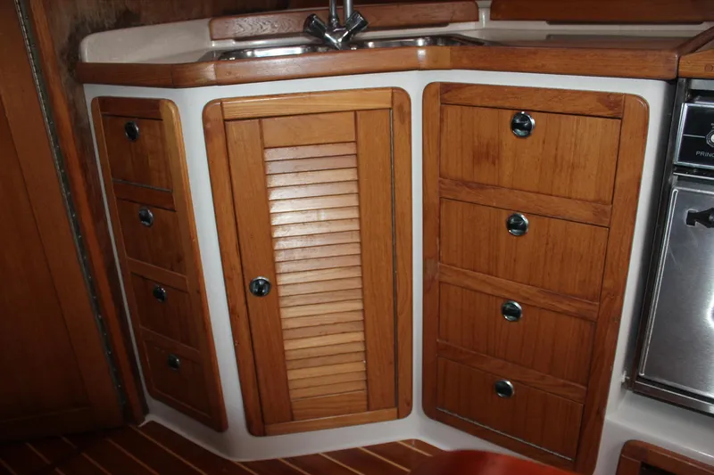 Slide: The Image of The galley of a 1999 Catalina 42 MkII with wooden cabinets and a stainless steel sink. - 26