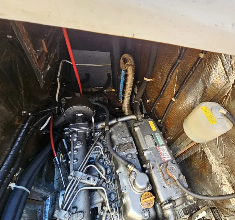 Slide: The Image of The engine compartment of a 1999 Catalina 42 MkII shows a well-maintained engine with hoses and cables. - 44