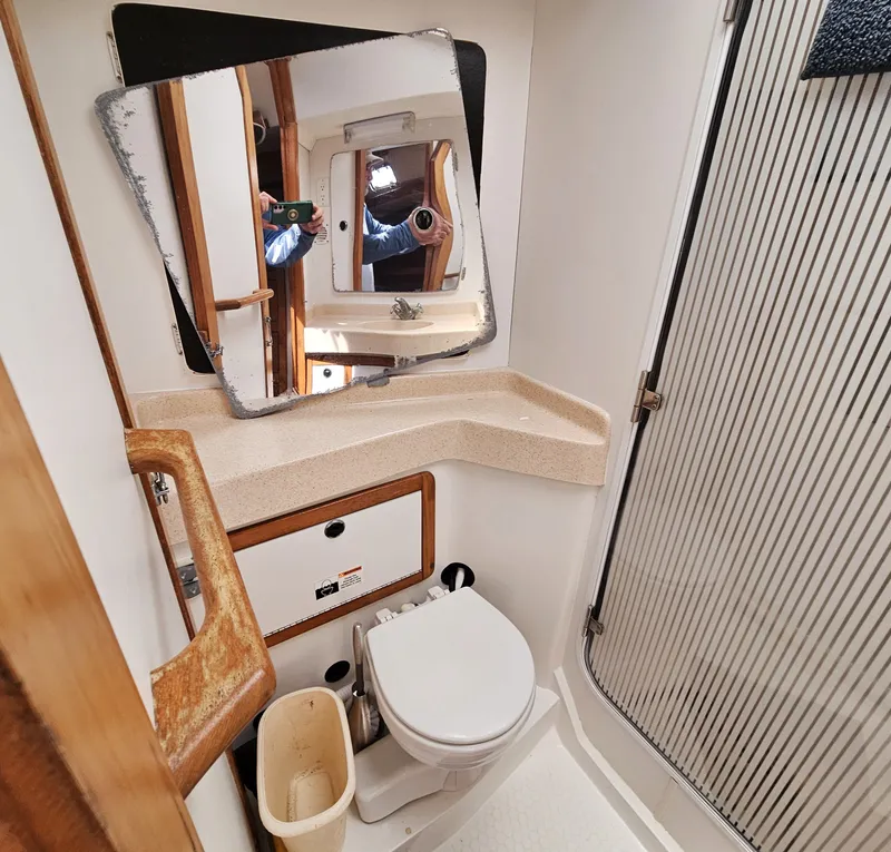 Slide: The Image of The image shows a boat bathroom with a toilet, mirror, and shower stall. - 19