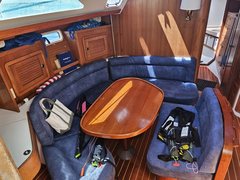 Slide: The Image of The interior of a 1999 Catalina 42 MkII features a cozy seating area with a wooden table. - 23