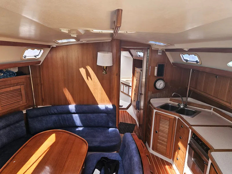Slide: The Image of Interior of a 1999 Catalina 42 MkII with wooden furnishings and blue upholstery. - 22
