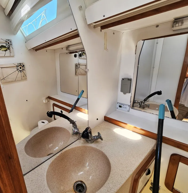 Slide: The Image of The image shows the bathroom of a 1999 Catalina 42 MkII with dual sinks and a mirror. - 38