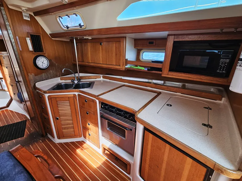 Slide: The Image of The galley of a 1999 Catalina 42 MkII with wooden cabinets, stove, and microwave. - 25