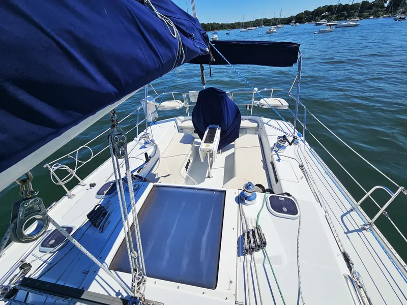 Slide: The Image of The image shows the deck of a 1999 Catalina 42 MkII with blue sails and a clear view of the water. - 13