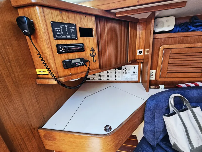 Slide: The Image of The navigation area of a 1999 Catalina 42 MkII with wood paneling and communication equipment. - 34