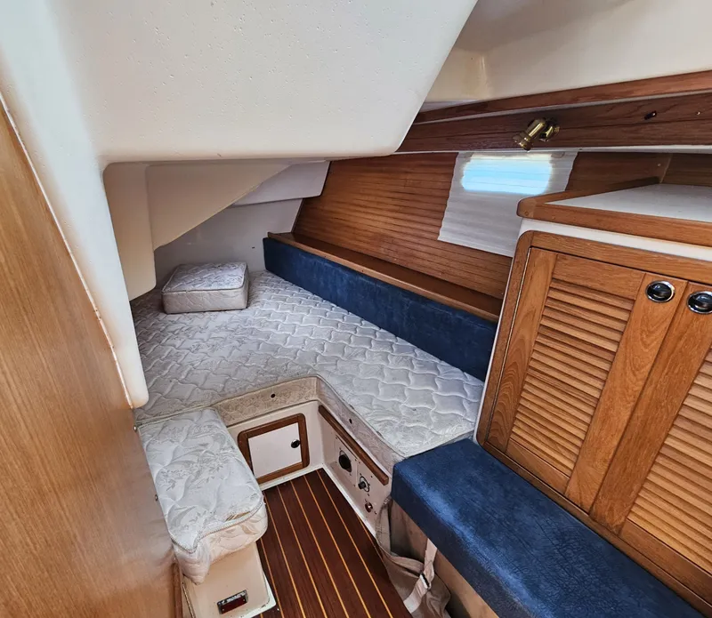 Slide: The Image of The cabin of a 1999 Catalina 42 MkII with wood paneling and blue upholstery. - 45