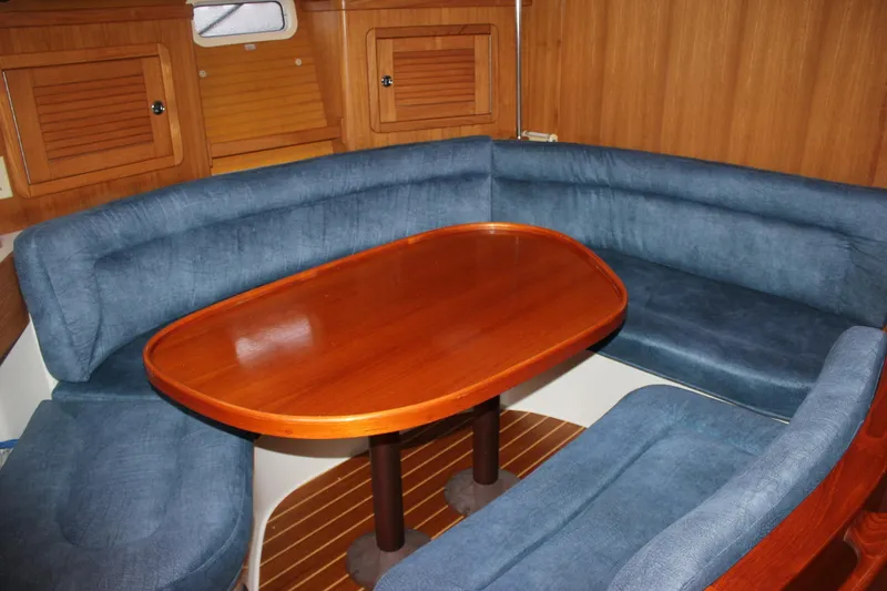 Slide: The Image of Interior of the 1999 Catalina 42 MkII with blue upholstery and a wooden table. - 24