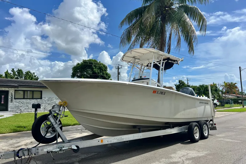 The Image of 2016 Sportsman Heritage 231 Center Console boat on trailer, parked under palm tree. - 0