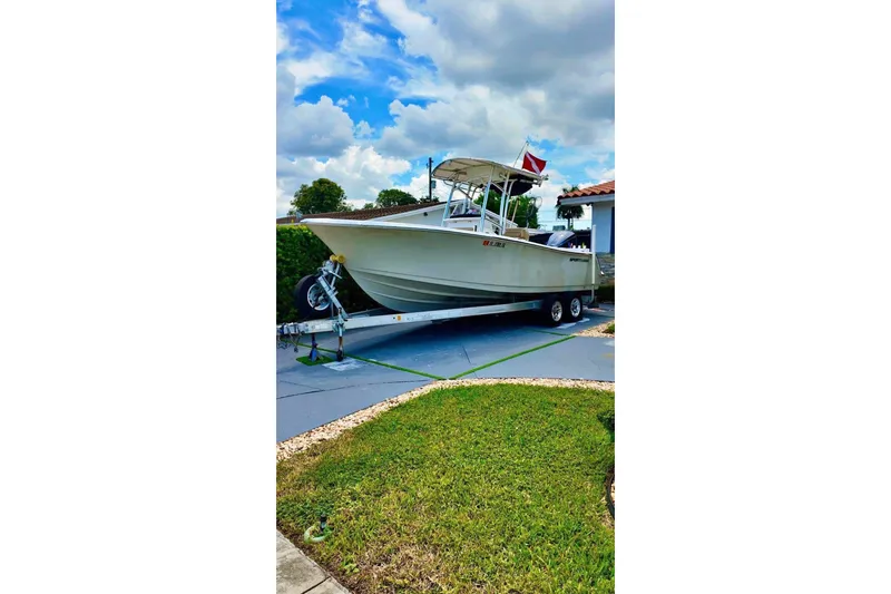 The Image of 2016 Sportsman Heritage 231 Center Console boat on trailer, parked in driveway. - 0