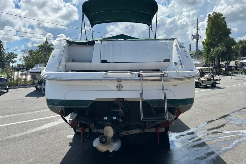 Slide: The Image of 1998 Cobalt 293 boat rear view with ladder, parked outdoors under cloudy sky. - 2