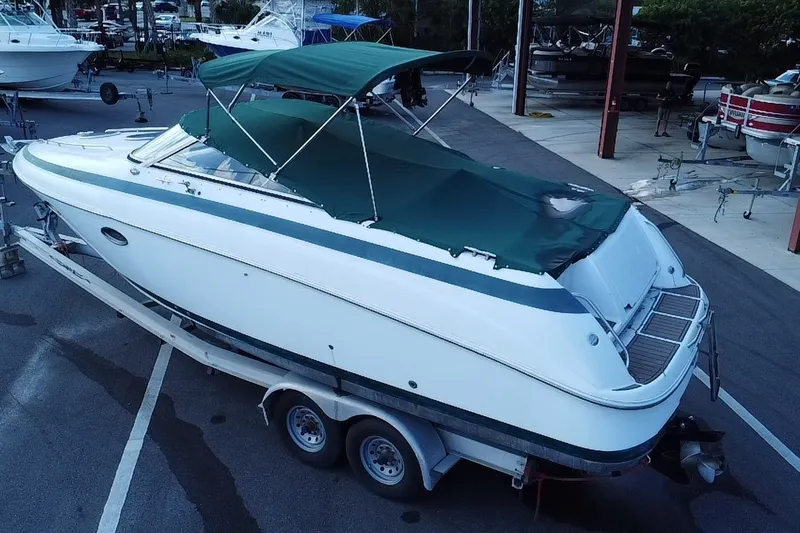 Slide: The Image of 1998 Cobalt 293 boat with green canopy on trailer in marina. - 6