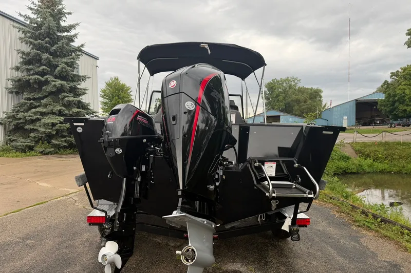 Slide: The Image of 2027 Starcraft Fishmaster 196 boat with dual outboard motors, parked near a marina. - 2
