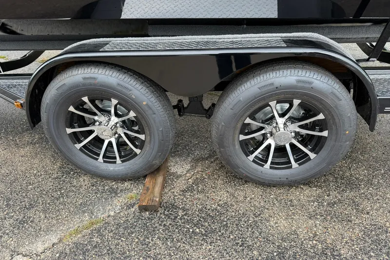 Slide: The Image of 2027 Starcraft Fishmaster 196 trailer wheels on pavement, featuring sleek black and silver rims. - 28