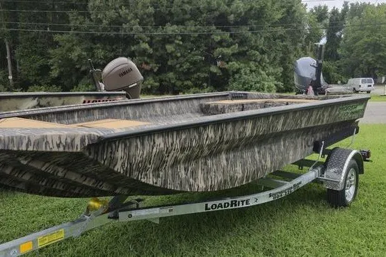 Slide: The Image of 2027 Havoc 1656 MRST MACH 1 boat on LoadRite trailer, camo design, parked on grass. - 16